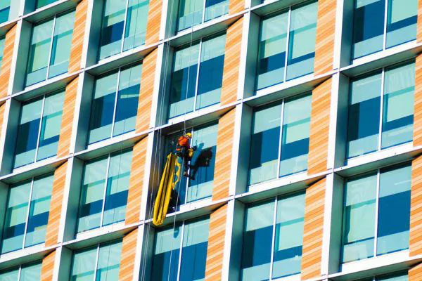 A man cleaning commercial buildings with multiple windows and floors