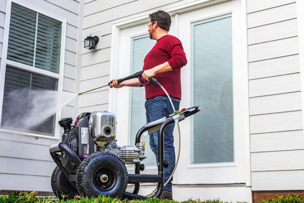 man using power washing ideas to clean window exterior